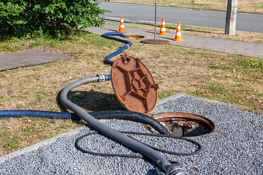 Open sewer manhole with hoses for maintenance Open sewer manhole with hoses for maintenance