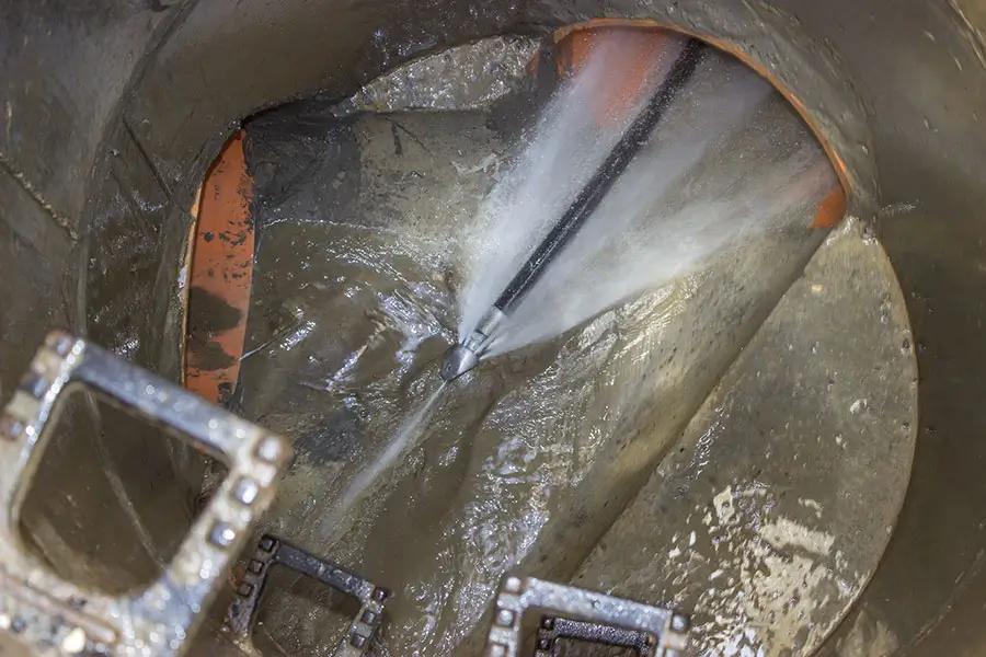 High-pressure water jet cleaning a sewer pipe