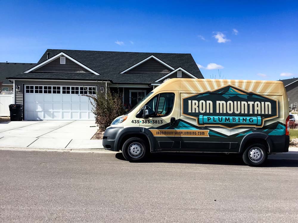 Iron Mountain Plumbing van parked in front of a house