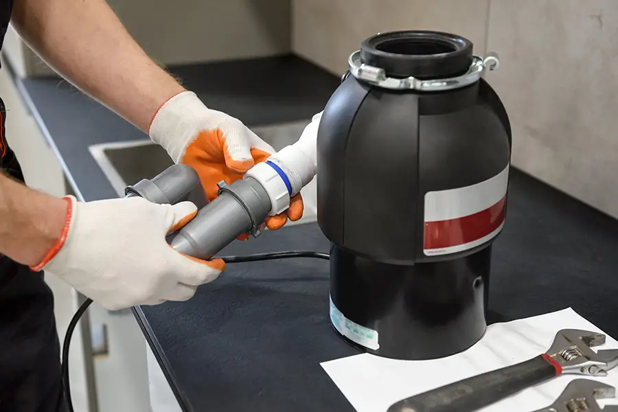 Plumber installing a garbage disposal unit.
